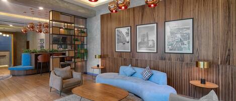A modern living room with a blue sofa, wooden flooring, and pendant lighting.