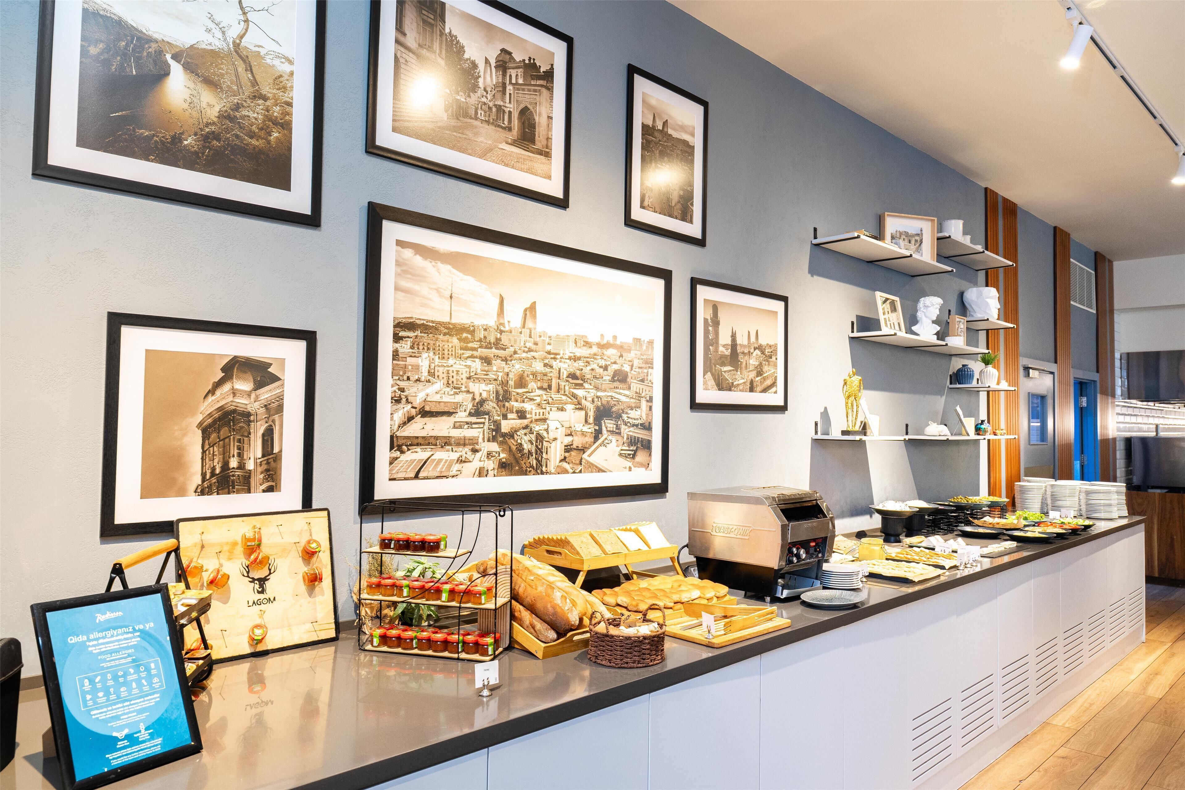 Ein Buffetbereich mit verschiedenen Speisen und einer Auswahl gerahmter Fotografien an der Wand.