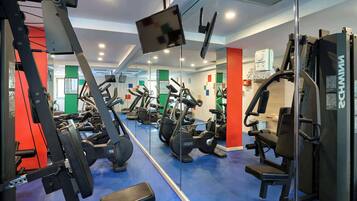 A gym with various exercise equipment, including treadmills, weight machines, and a mirrored wall.