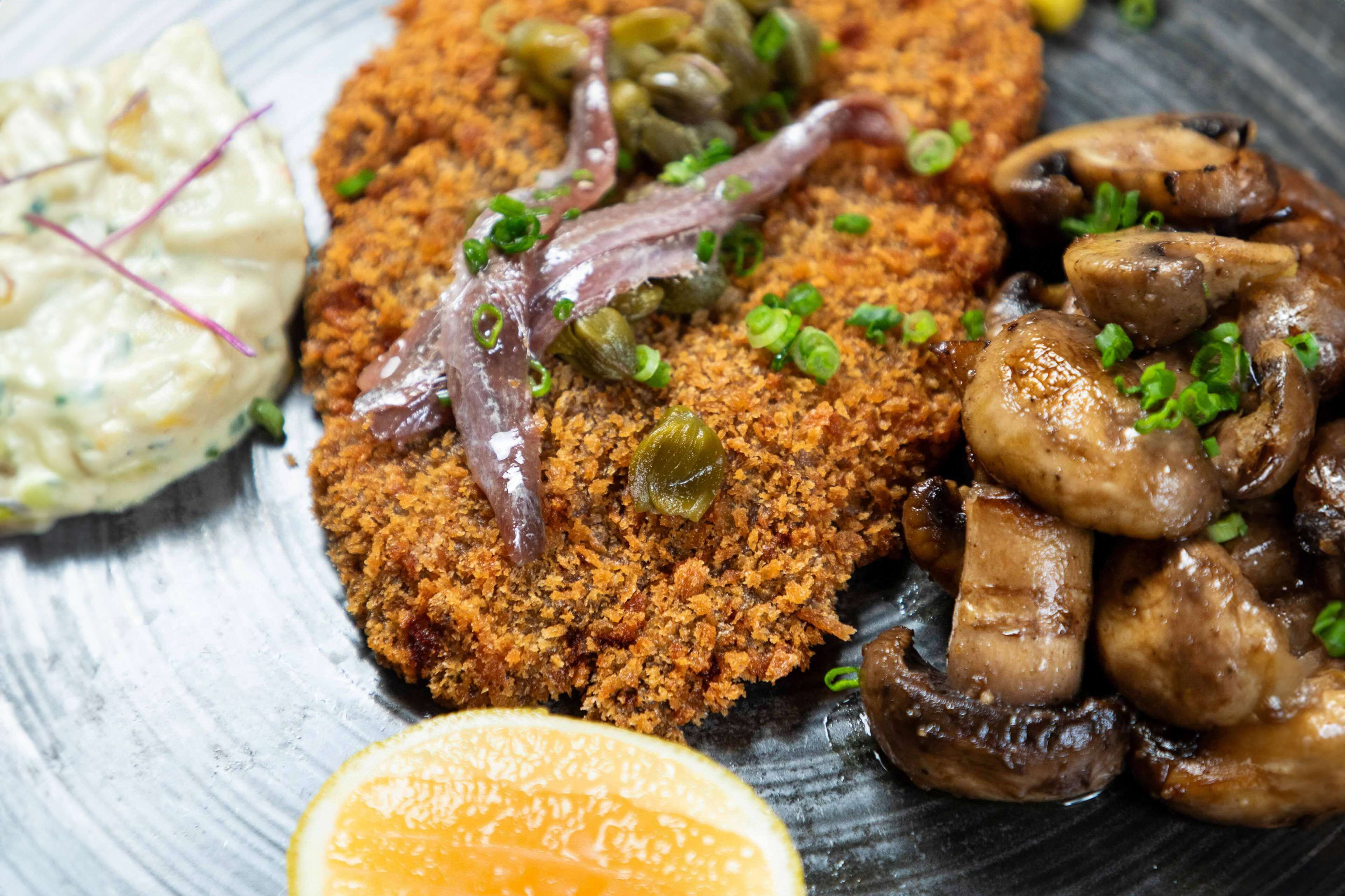 A plate with a breaded cutlet, mushrooms, and a side salad.