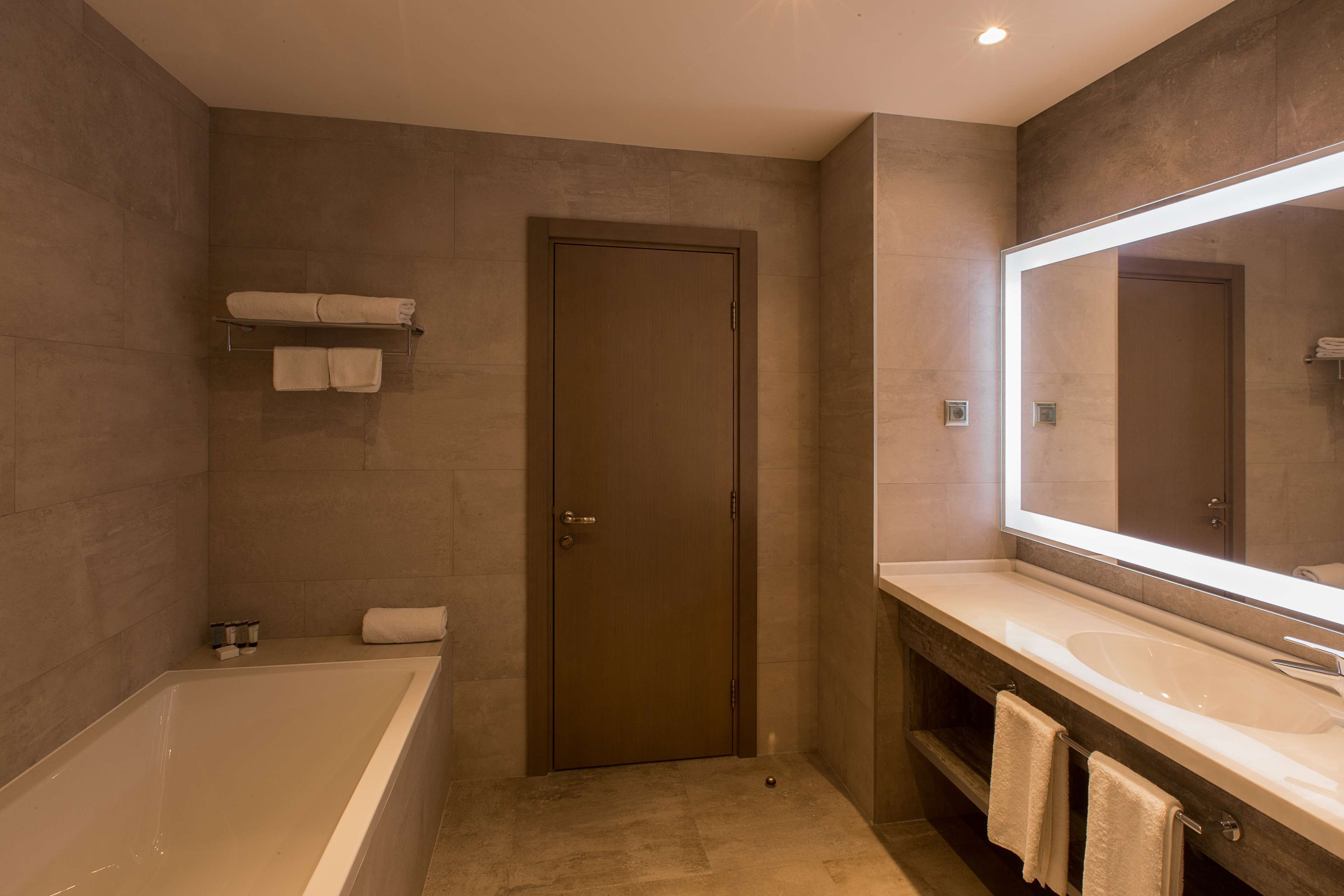 A modern bathroom with a bathtub, a large mirror, and a vanity with a sink.