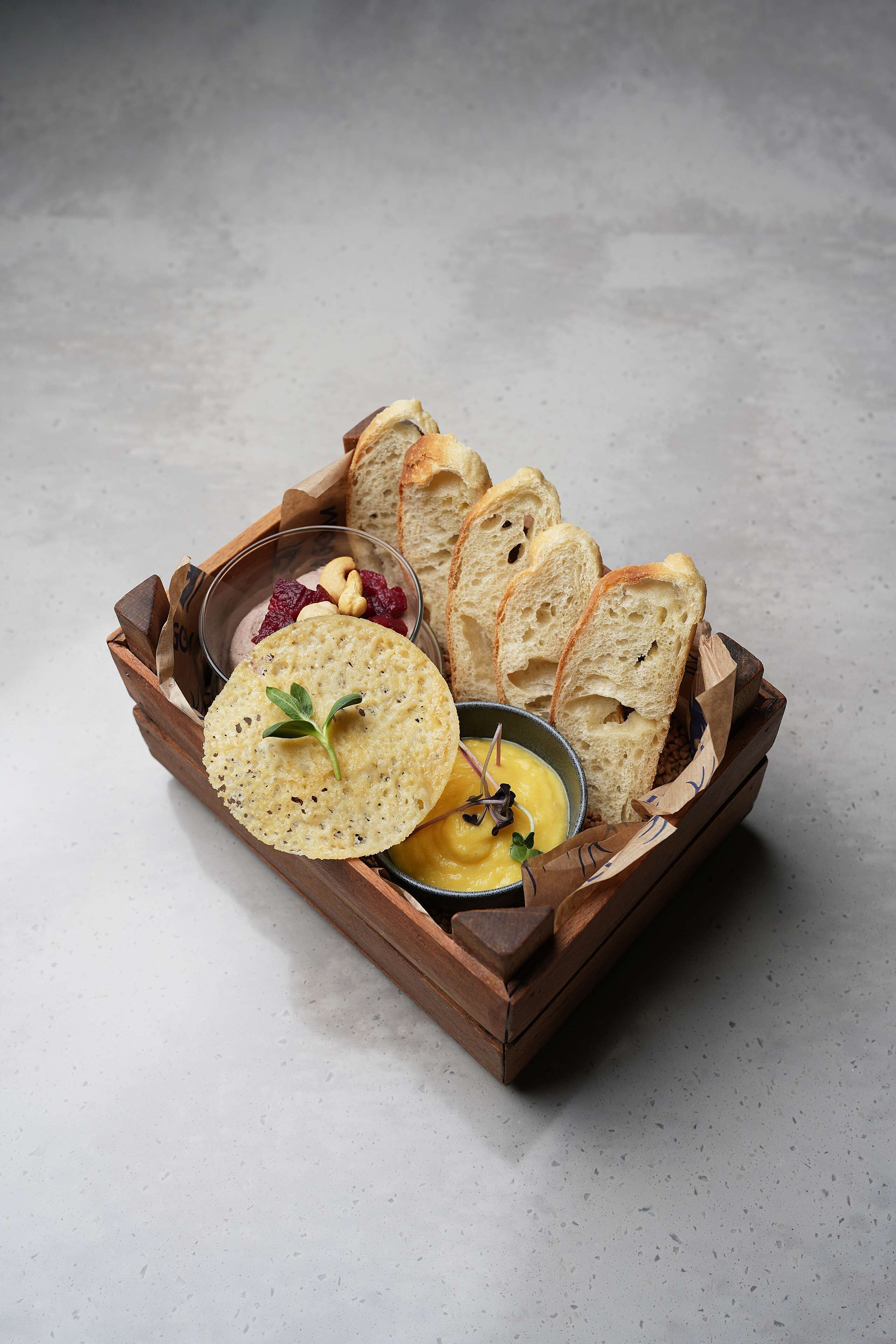 A wooden tray with slices of bread, a bowl of dip, and some berries.