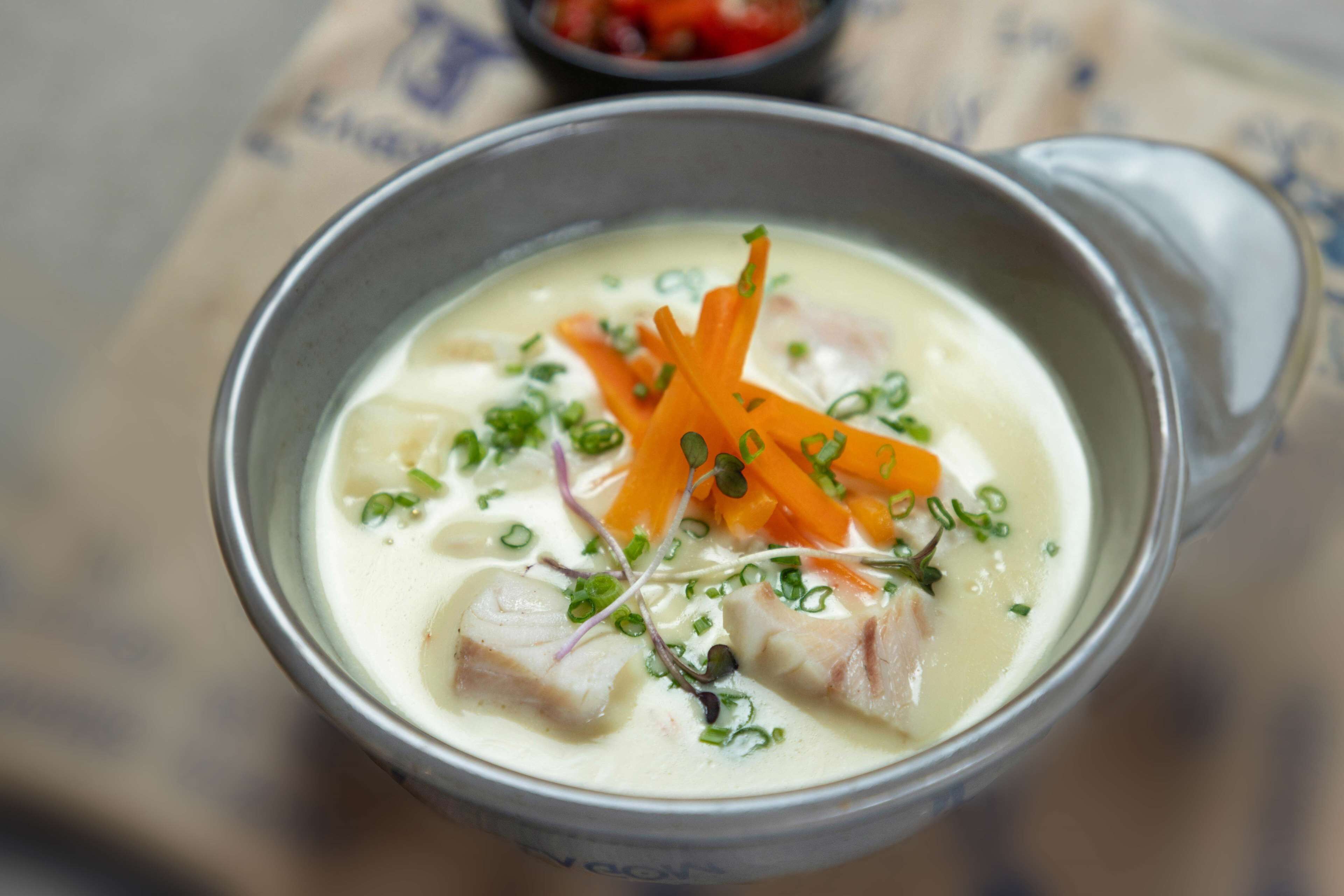 Un tazón de sopa con zanahorias y hierbas.