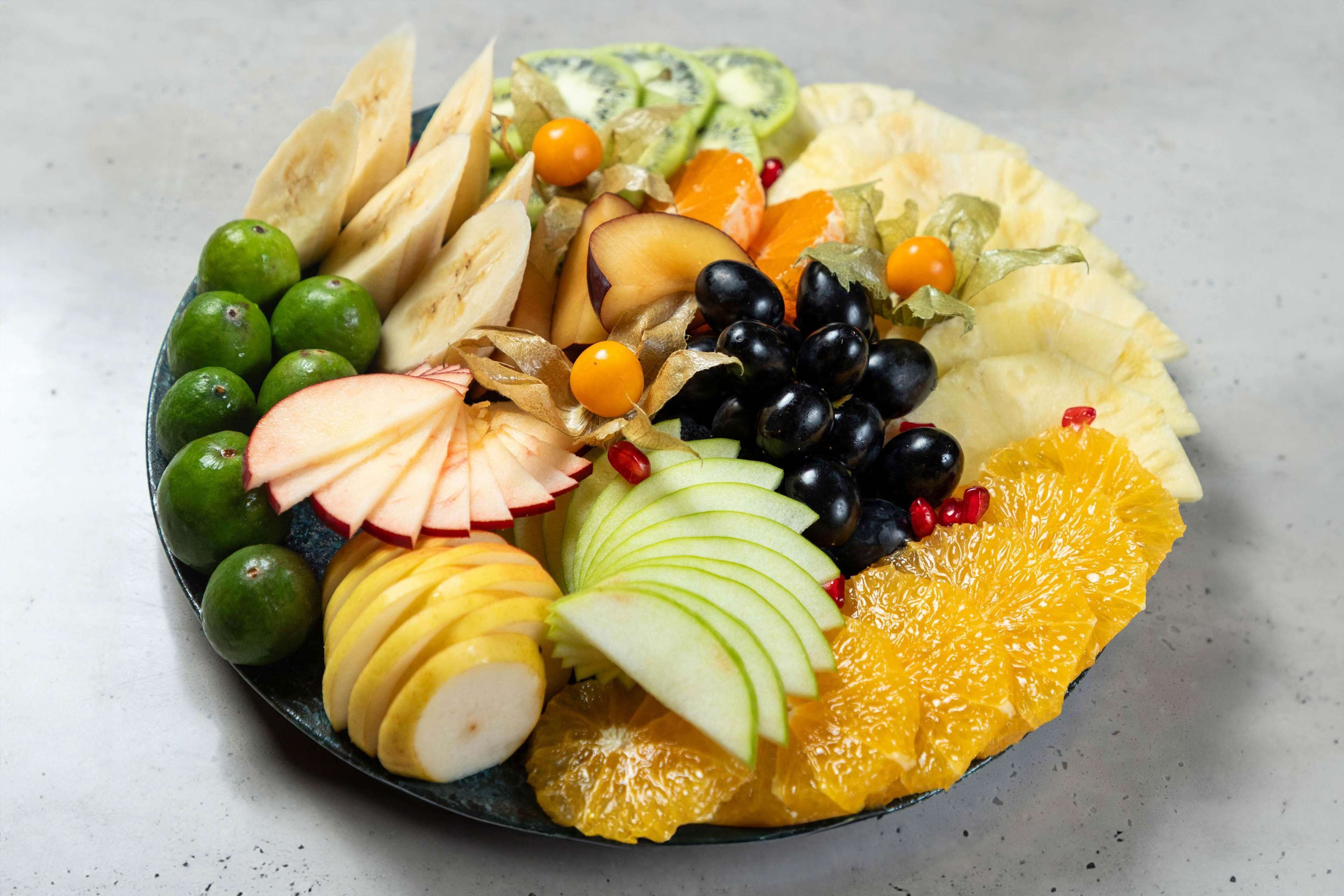 Una bandeja de frutas con diversas variedades, como manzanas, naranjas y uvas.
