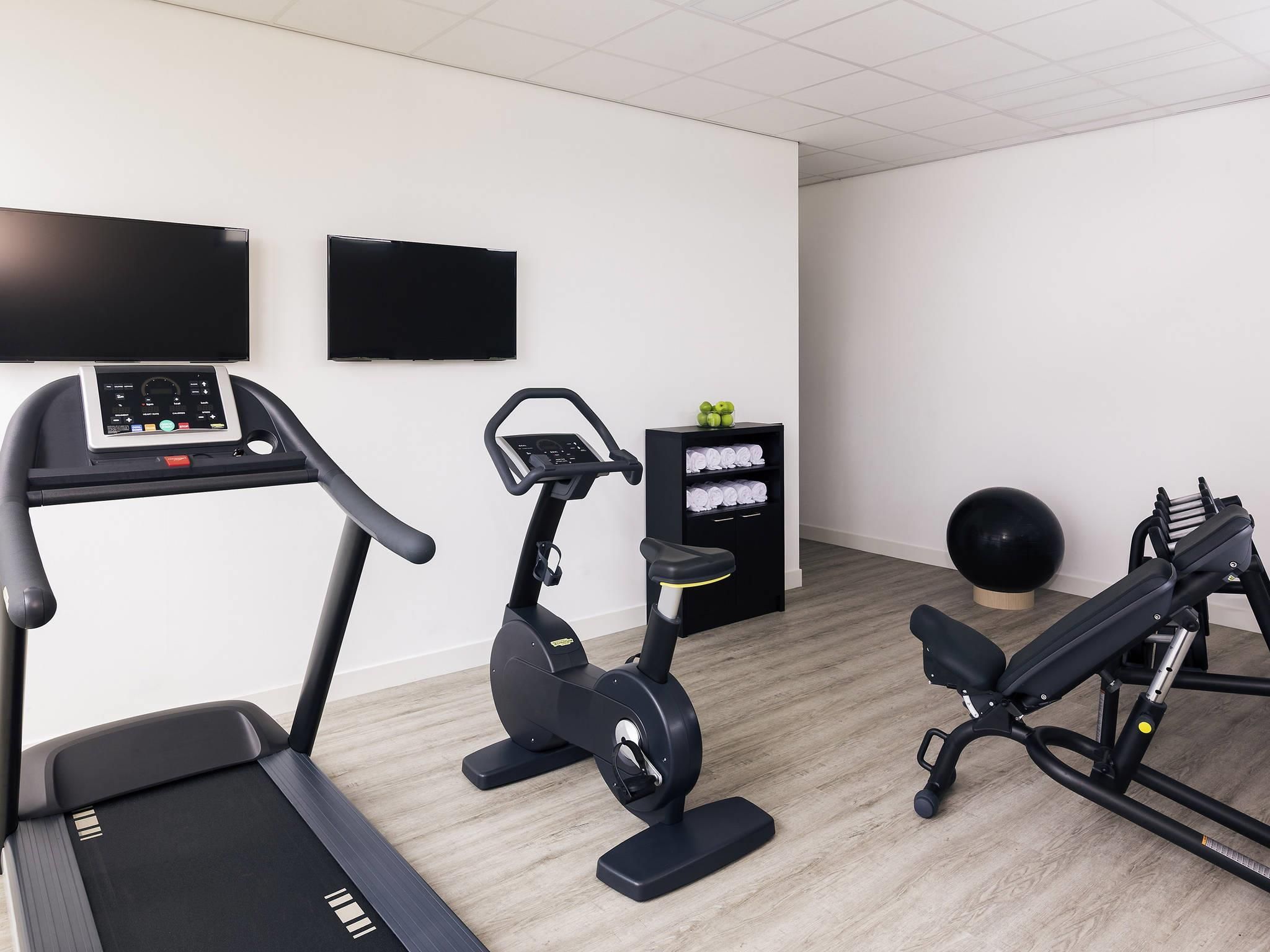 Ein Fitnessraum mit Laufband, Crosstrainer und Gewichtbank.