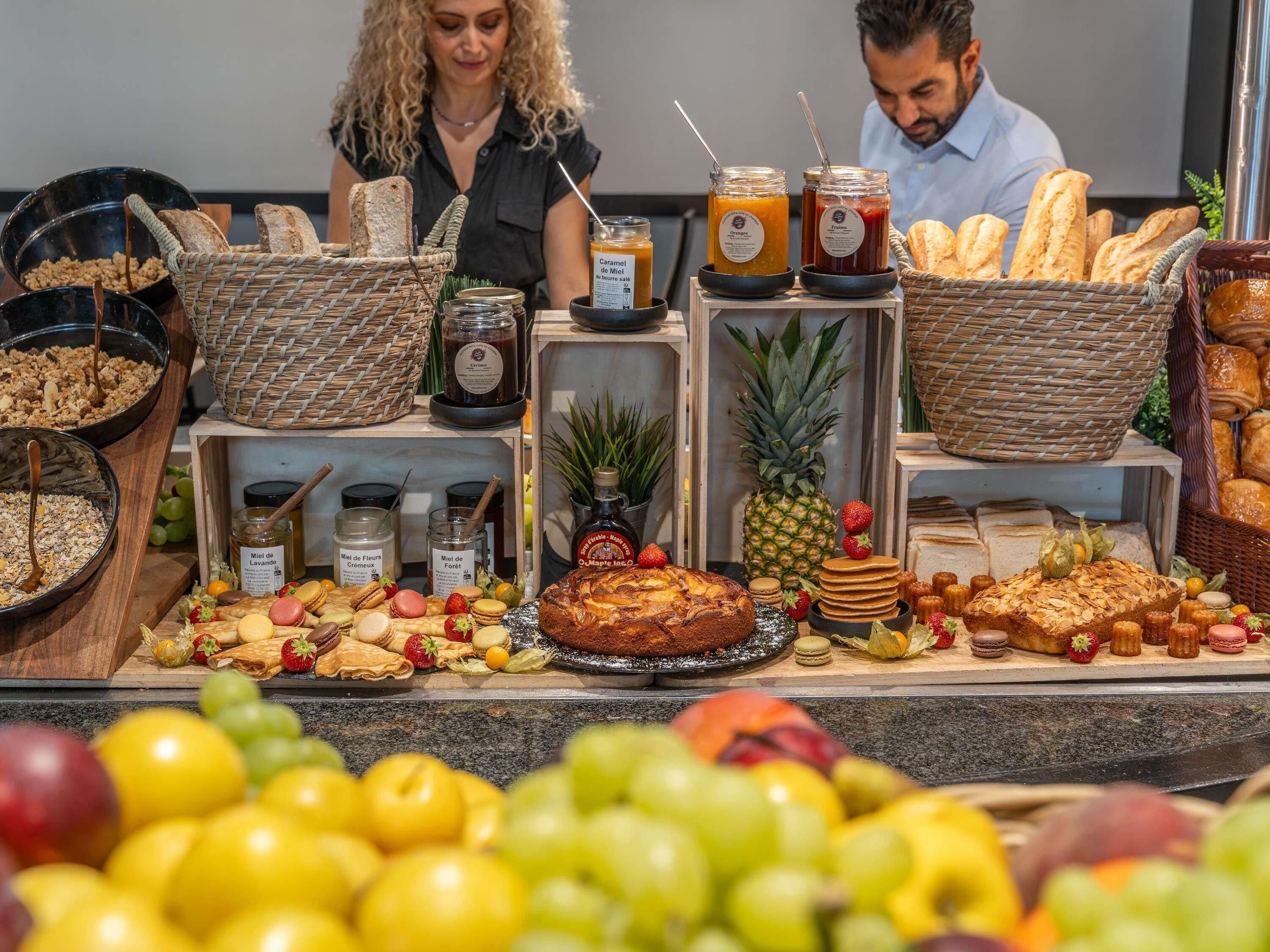 Un buffet proposant une variété de plats, notamment des fruits, des pâtisseries et des condiments.