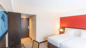 Une chambre d’hôtel équipée d’un lit, d’un bureau, d’une chaise et d’un téléviseur.