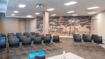 A conference room with rows of chairs, a projector, a laptop, and a water bottle on a table.