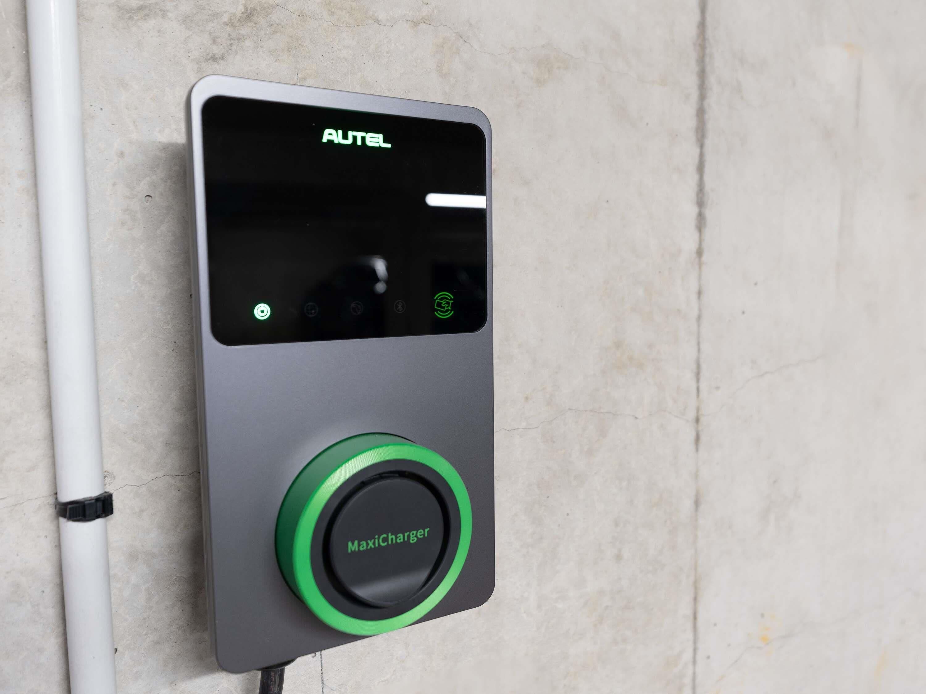 A wall-mounted device with a digital display and a green button labeled 'MaxiCharger.'