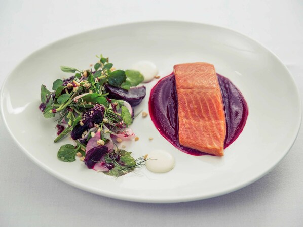 A white plate with a piece of salmon and a salad.