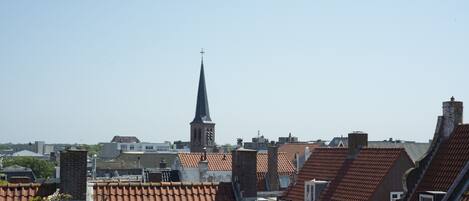 A cityscape with a prominent church steeple and terracotta-tiled rooftops.