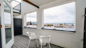 A balcony with a view of the beach, a table, and two chairs. - Amsterdam Beach Hotel (Zandvoort)