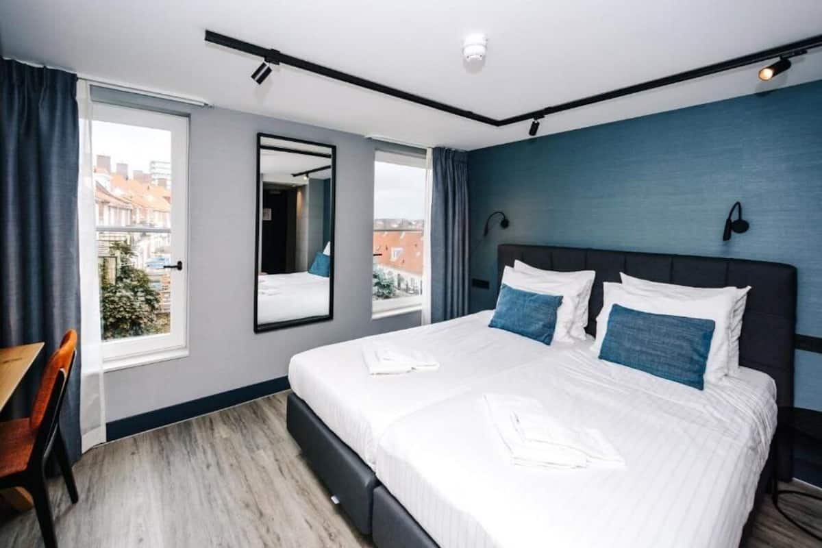 Une chambre d’hôtel moderne dotée d’un grand lit, d’un bureau et d’une fenêtre donnant sur la ville.