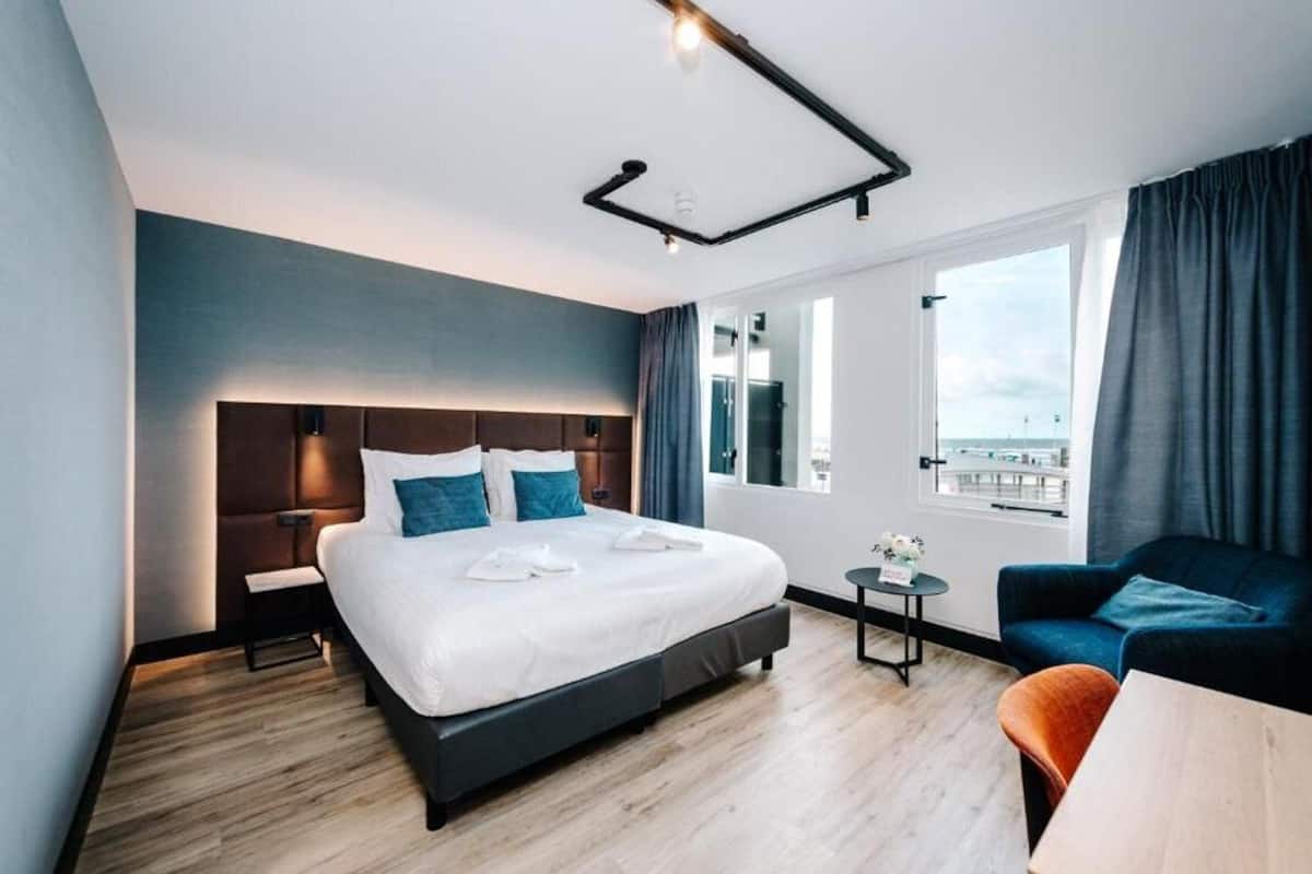 Une chambre d’hôtel moderne avec un grand lit, un canapé, une petite table et une vue sur la ville.