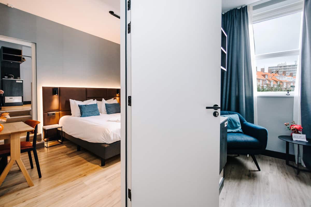 Une chambre d’hôtel moderne équipée d’un lit, d’un bureau, d’une chaise et d’une petite table sur laquelle se trouve un vase.