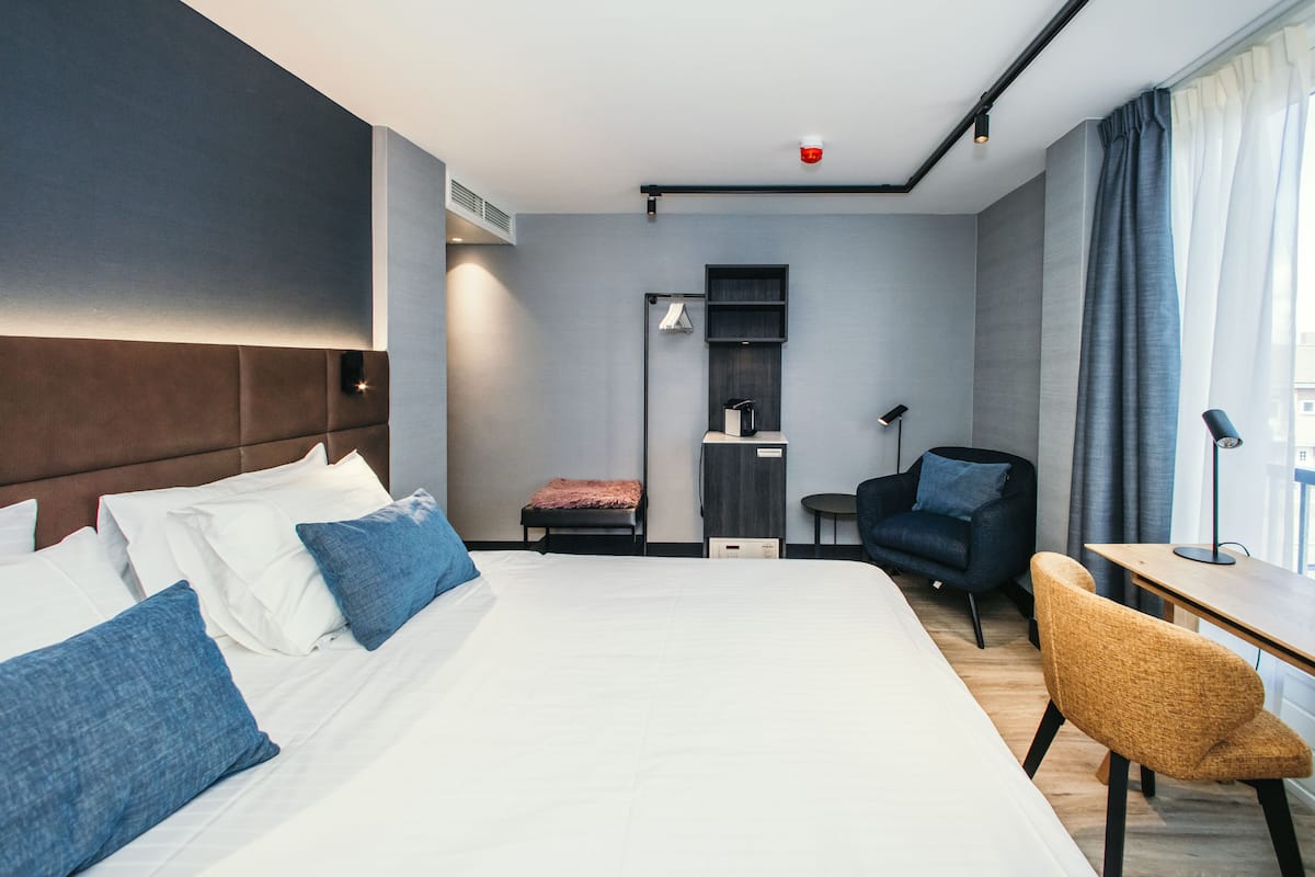 Une chambre d’hôtel moderne avec un grand lit, un bureau, une chaise et une petite table.