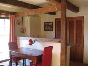A dining area with a wooden table and chairs, a vase with flowers, and a wooden ceiling with decorative elements.