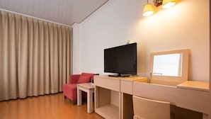 Une chambre moderne équipée d’un bureau, d’une télévision et d’une fenêtre avec des rideaux.