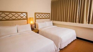 A hotel room with two beds, a headboard with a scalloped design, a bedside lamp, and a window with curtains. - Prince Hotel (Jiaoxi)