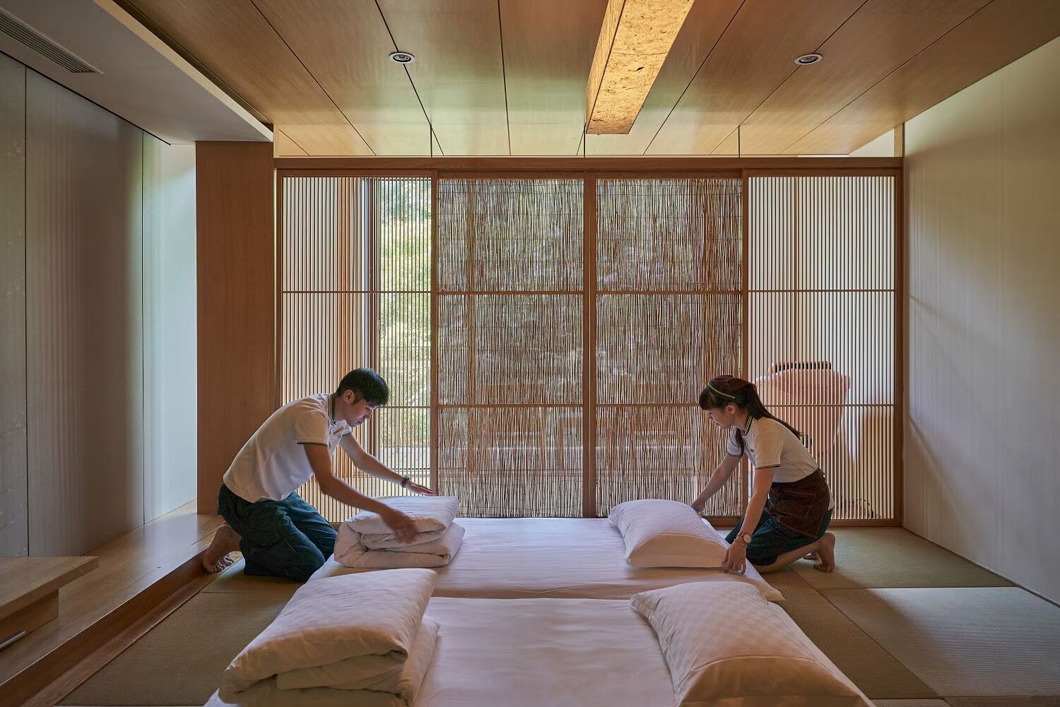 A traditional Japanese-style room with tatami flooring, sliding shoji screens, and a low wooden ceiling.