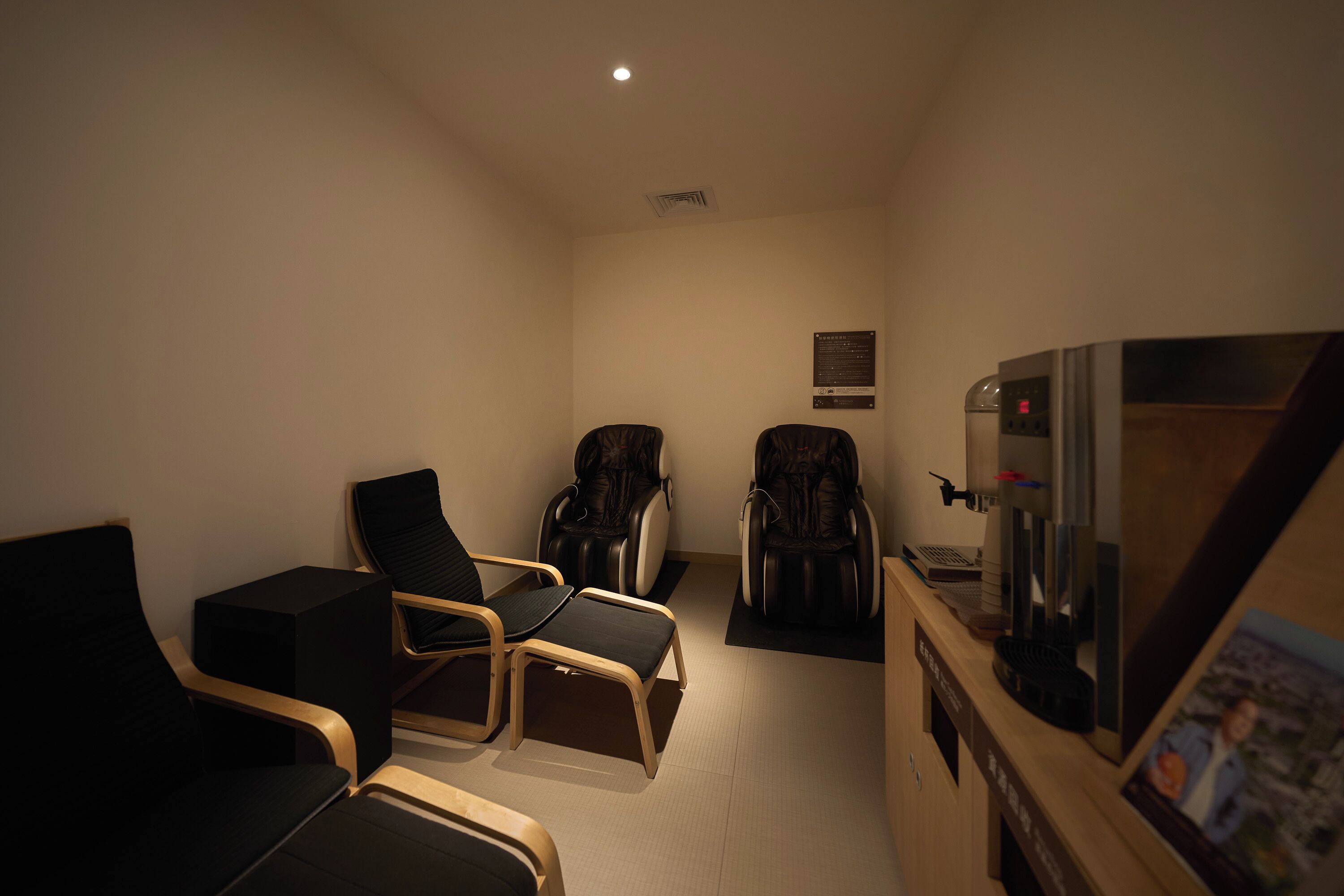 Una habitación con dos sillones de masaje, un sofá, una mesita y un refrigerador.