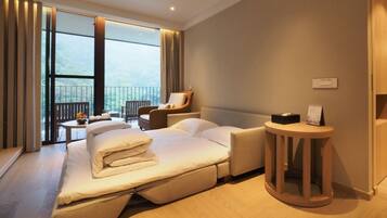 A modern hotel room with a large bed, a seating area with a table, and a view of the outdoors.