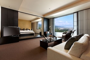 Une chambre d’hôtel moderne dotée d’un grand lit, d’une télévision, d’un canapé et d’un balcon offrant une vue sur la ville.