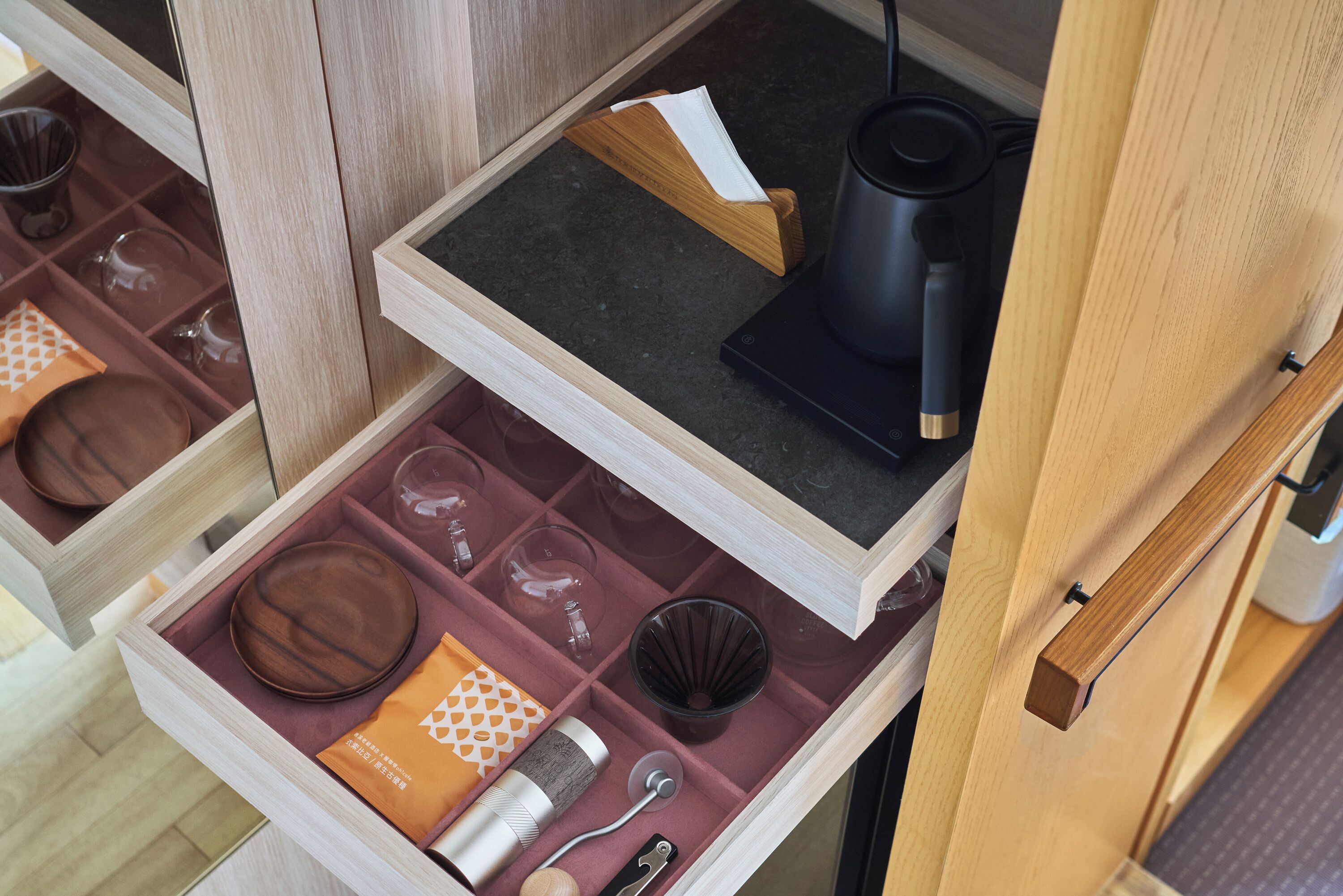 A drawer with neatly organized kitchenware, including plates, bowls, and a coffee maker.