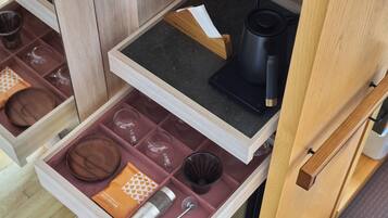 A drawer with neatly organized kitchenware, including plates, bowls, and a coffee maker.
