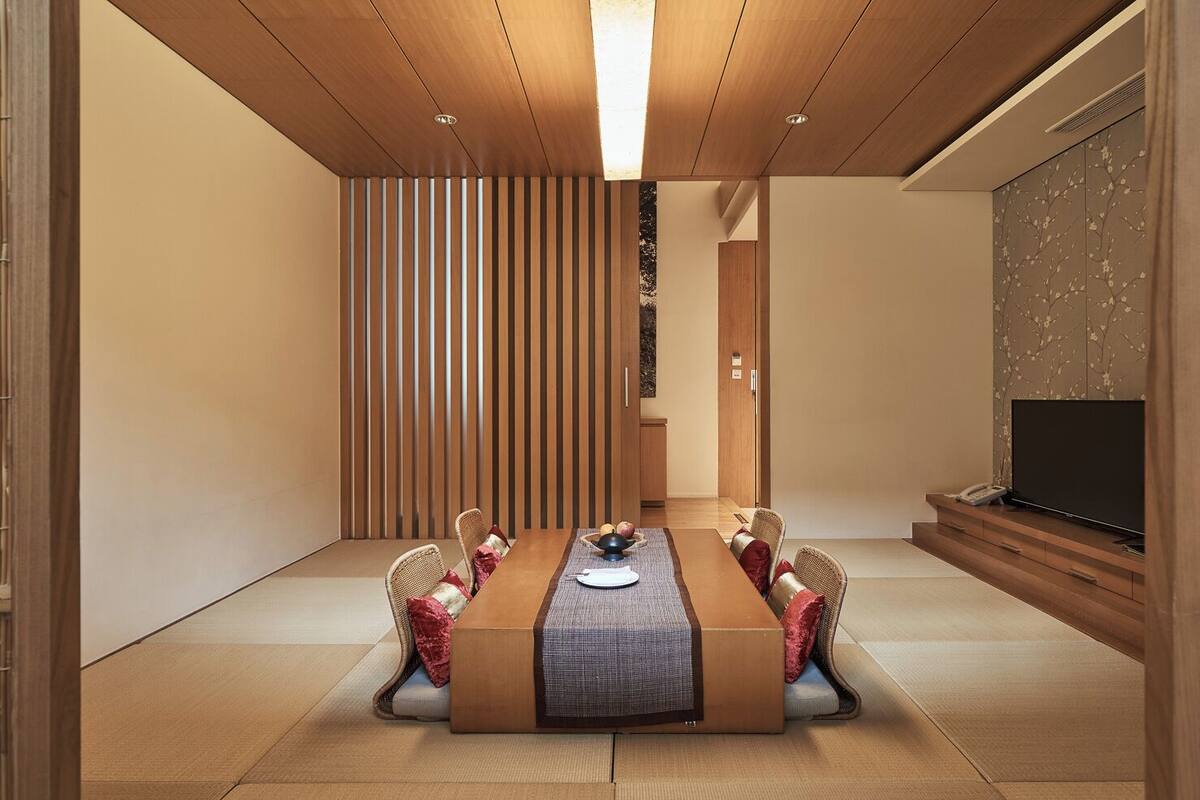 Un comedor moderno con una mesa larga, sillas y un televisor sobre un mueble.