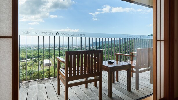 Un balcon doté de mobilier en bois et offrant une vue sur un paysage verdoyant.