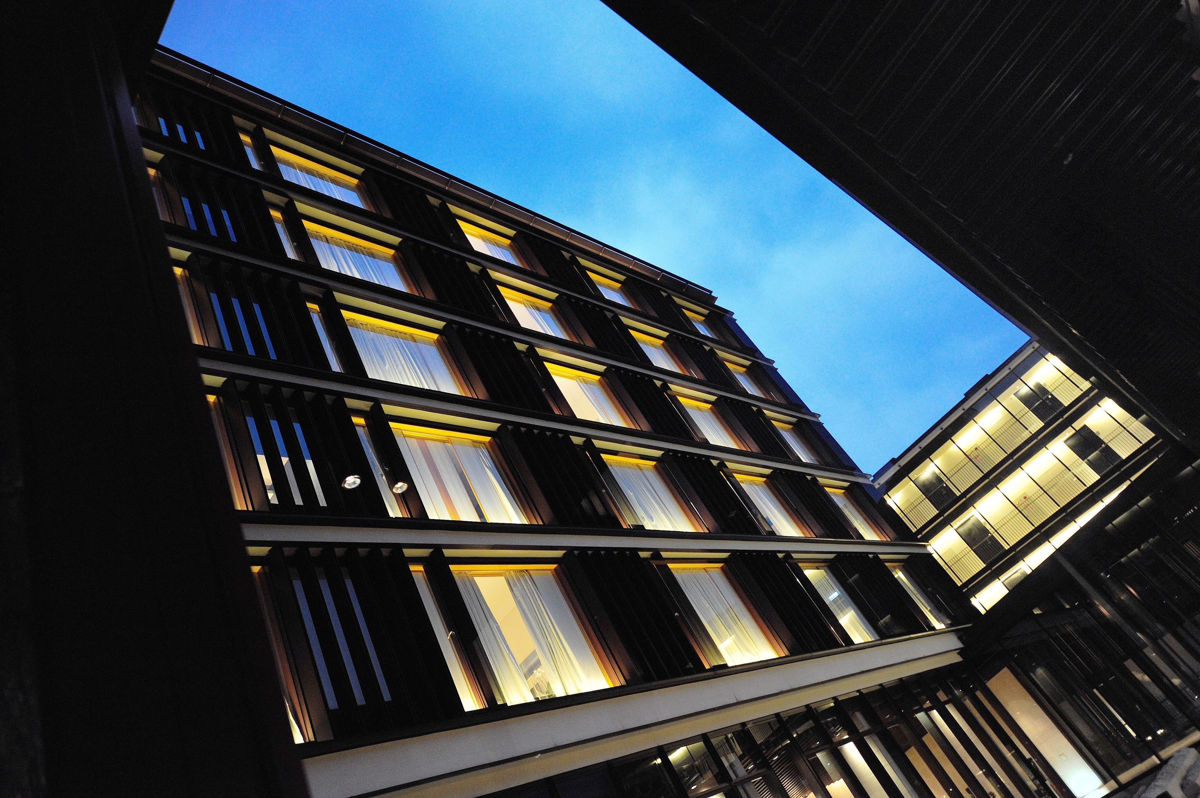 A modern building with a series of illuminated windows and a clear sky in the background.