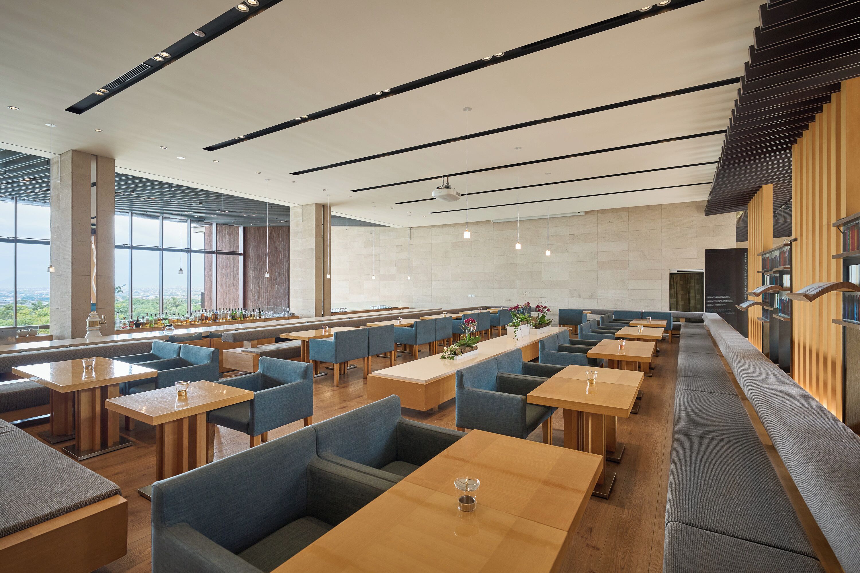 A modern restaurant with high tables and booths, large windows, and a bar area.
