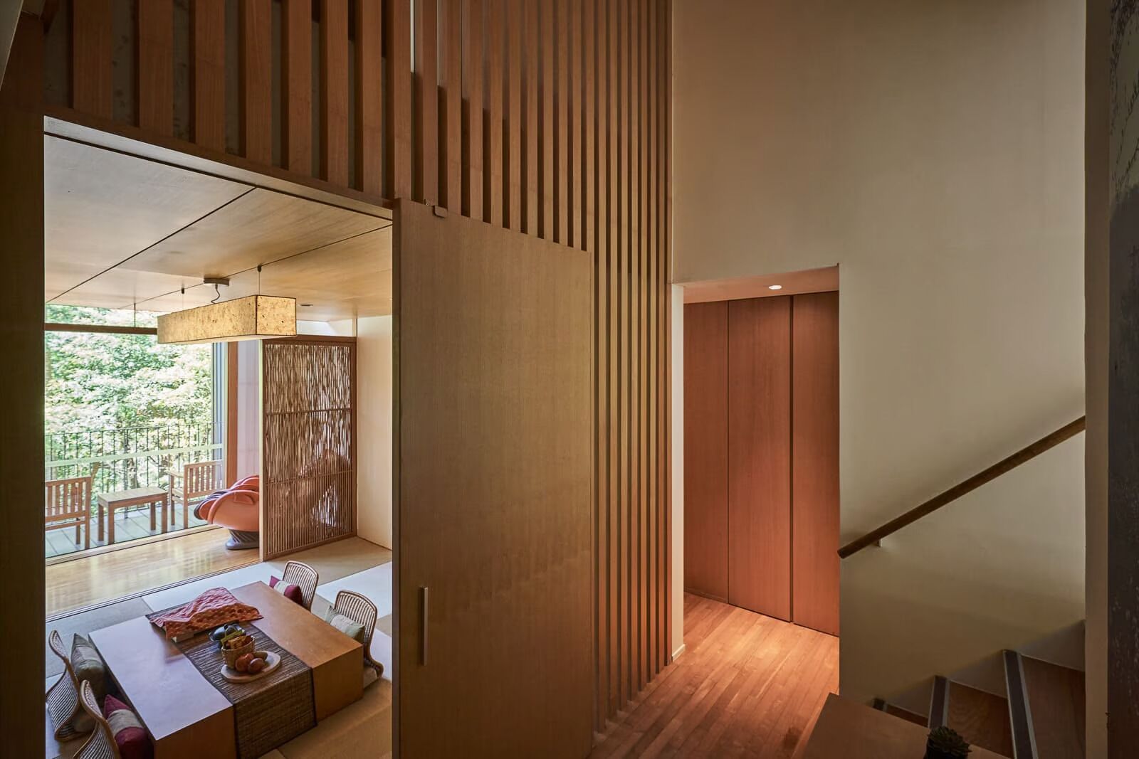 Un interior moderno con comedor, paneles de madera y una escalera.