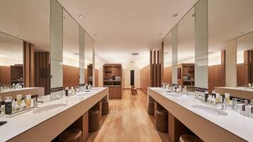 A modern bathroom with two sinks, wooden cabinets, and a central seating area.