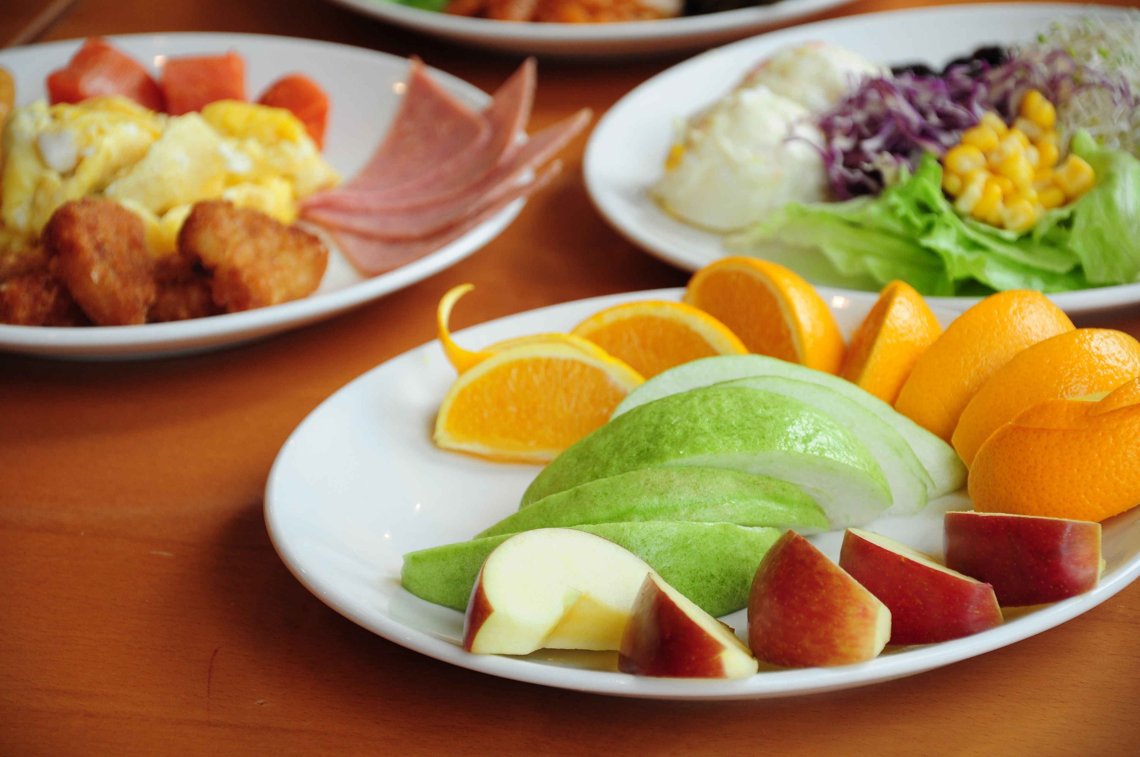 Una mesa con varios platos de comida, incluyendo frutas y verduras.