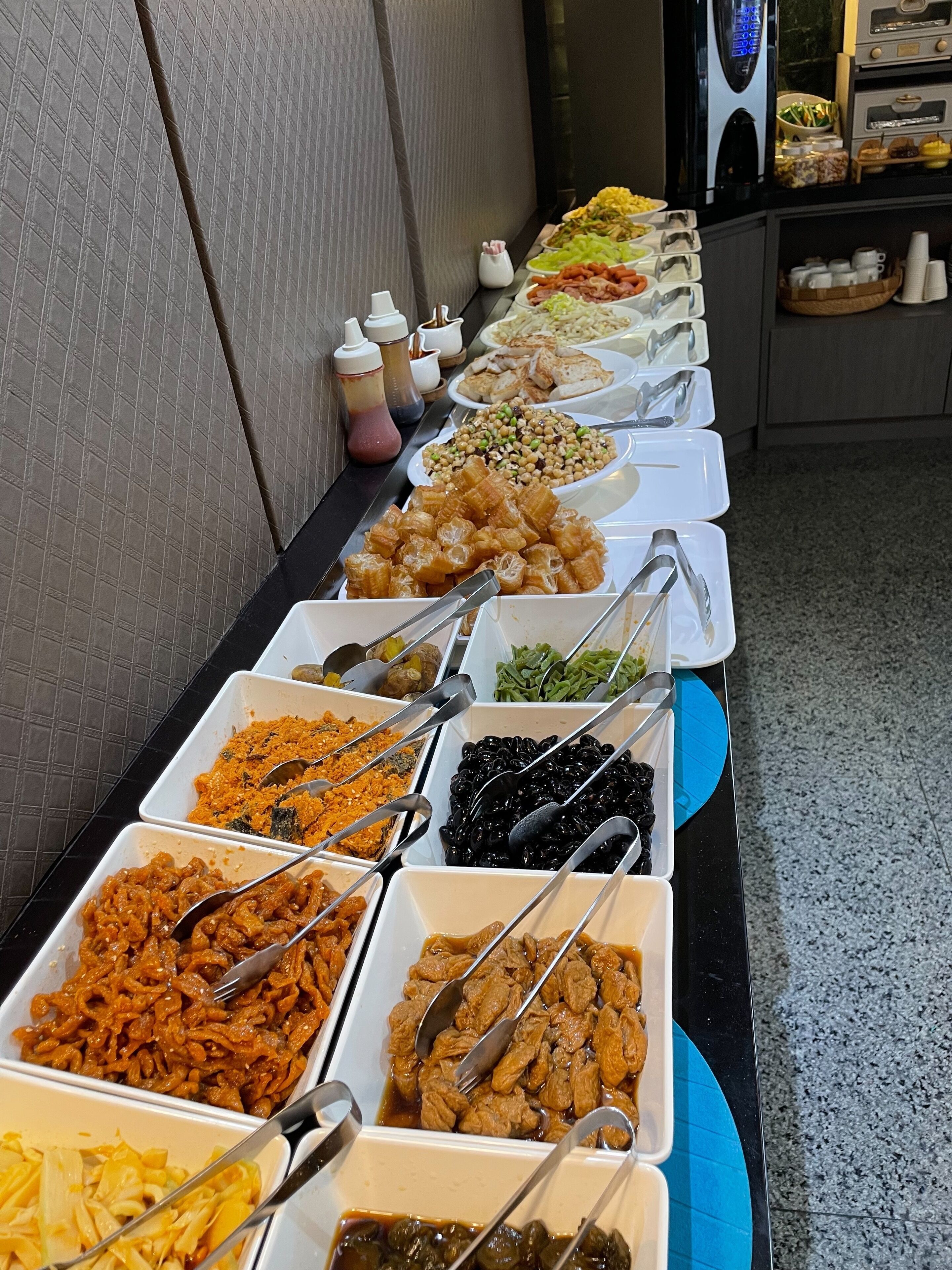 Un bufé con diversos platos dispuestos en fuentes, entre ellos fideos, carnes y verduras.