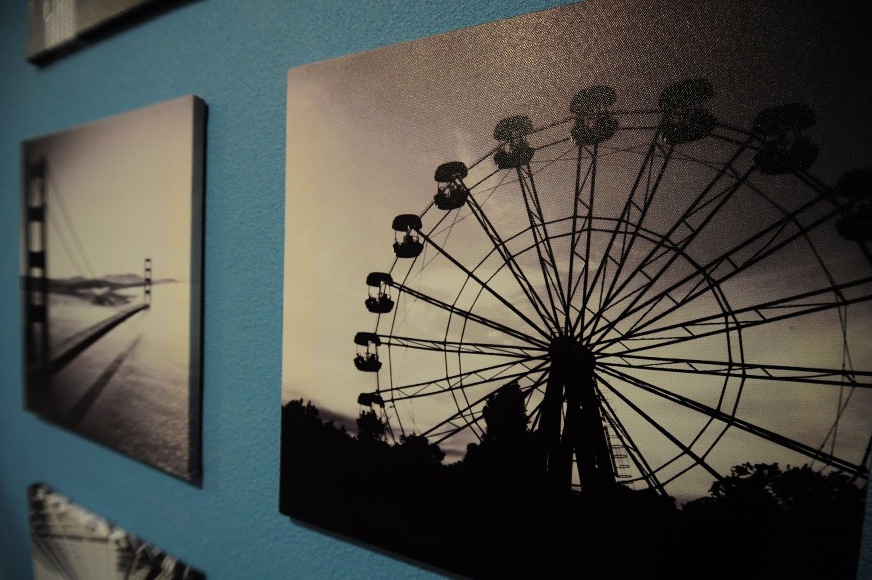 A wall with three framed pictures: a bridge, a Ferris wheel, and a ship.