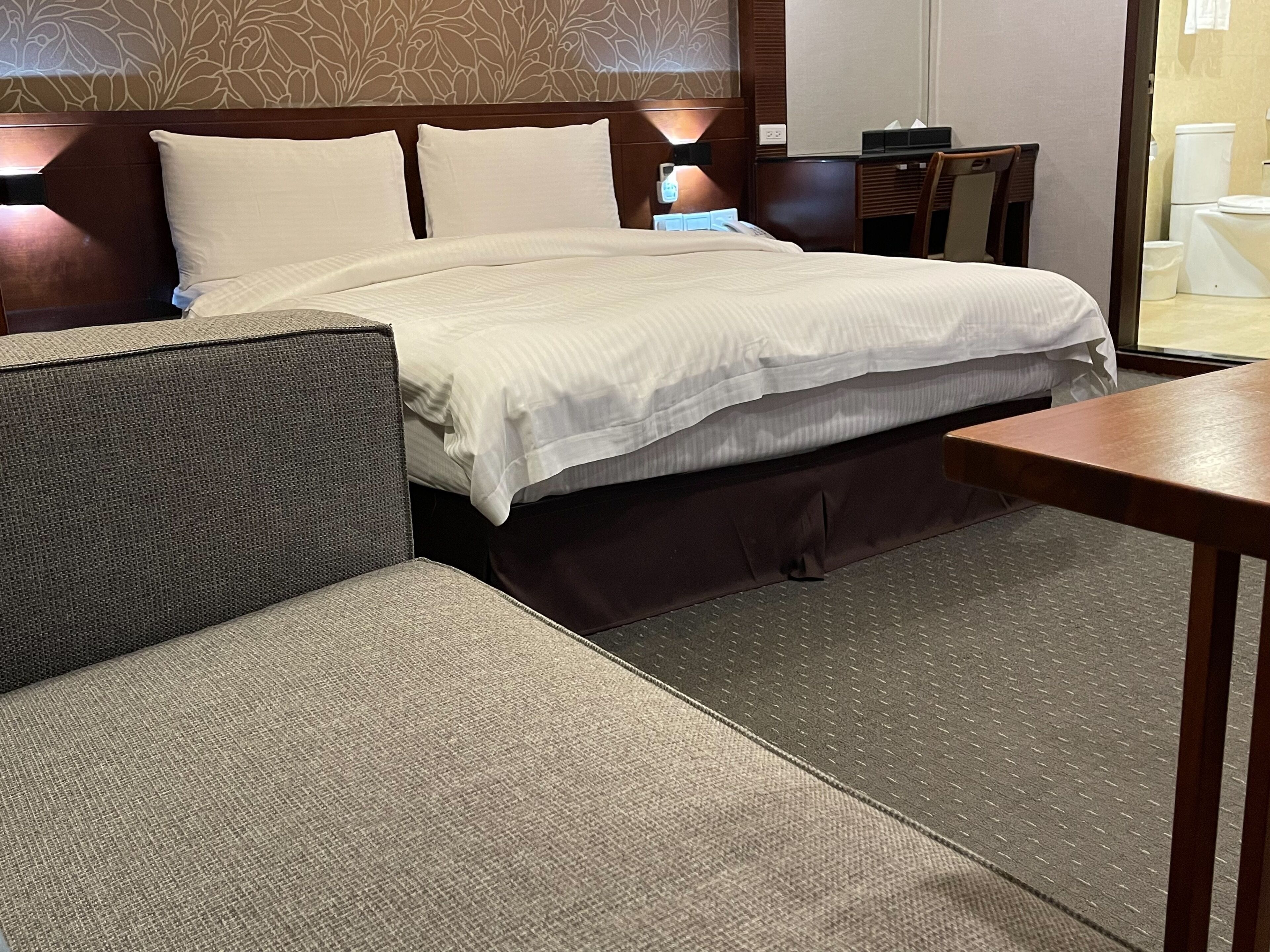 Ein Hotelzimmer mit Bett, Sofa, einem kleinen Tisch und einem Nachttisch.
