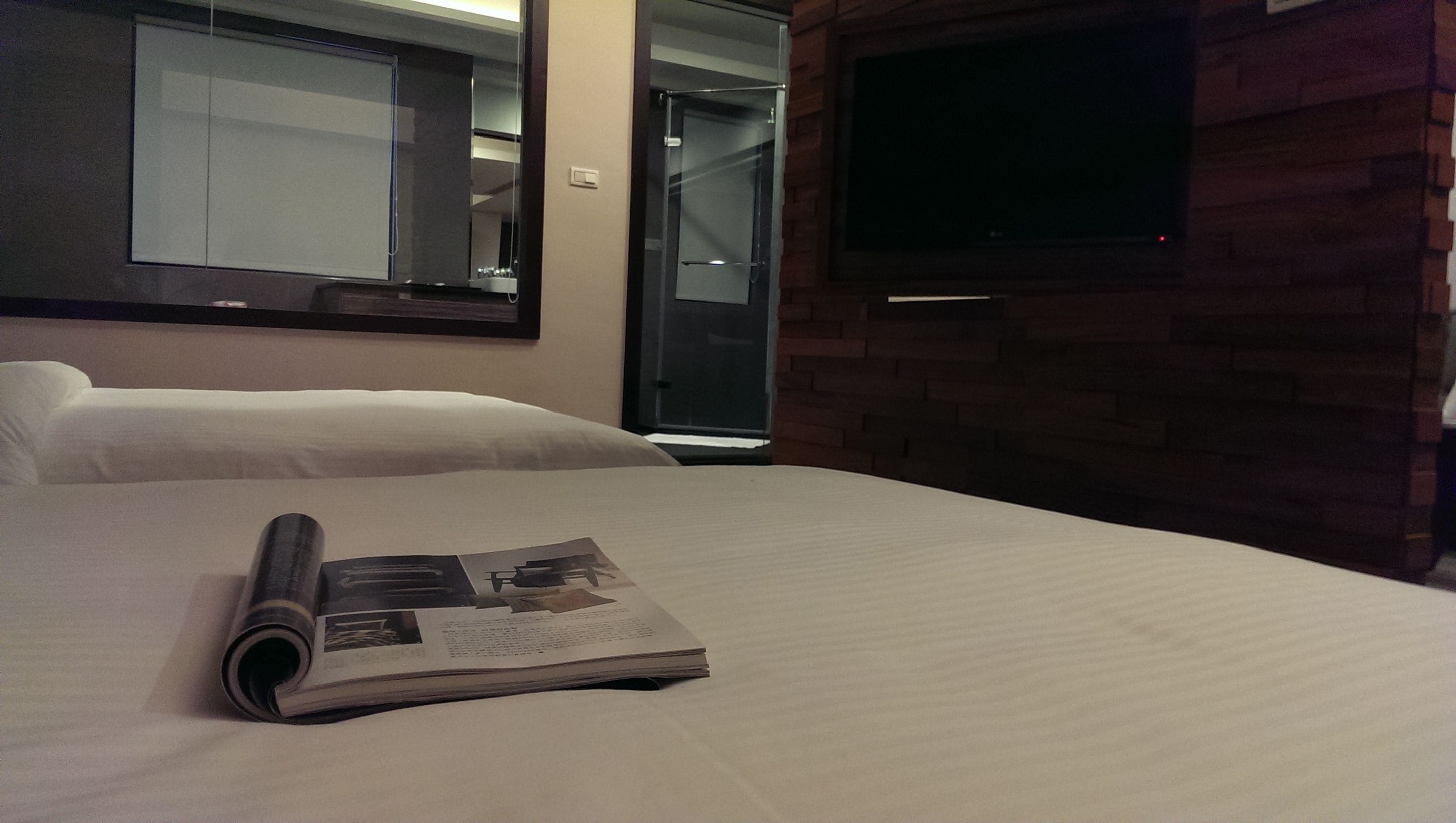 Een hotelkamer met een bed, een wandtelevisie en een deur naar een badkamer.