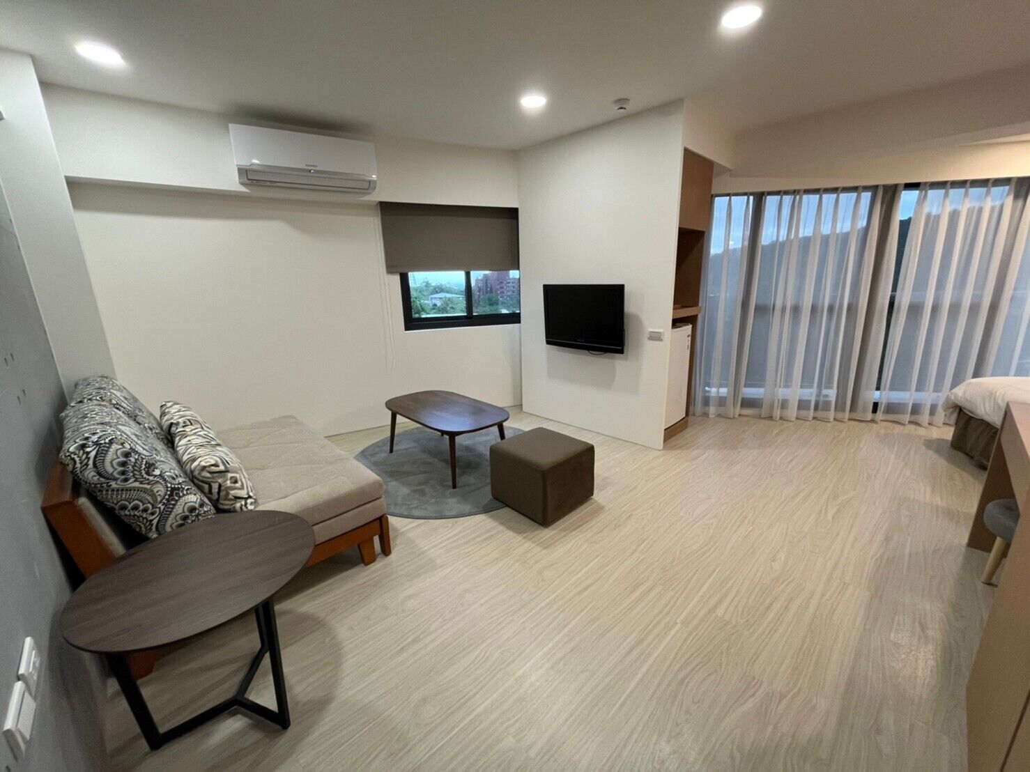 Un salon moderne comprenant un canapé, une table basse, un téléviseur fixé au mur et une porte-fenêtre coulissante donnant sur un balcon.
