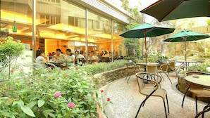An outdoor dining area with tables and chairs, surrounded by greenery and plants. - Liga Hotel (Hualien City)
