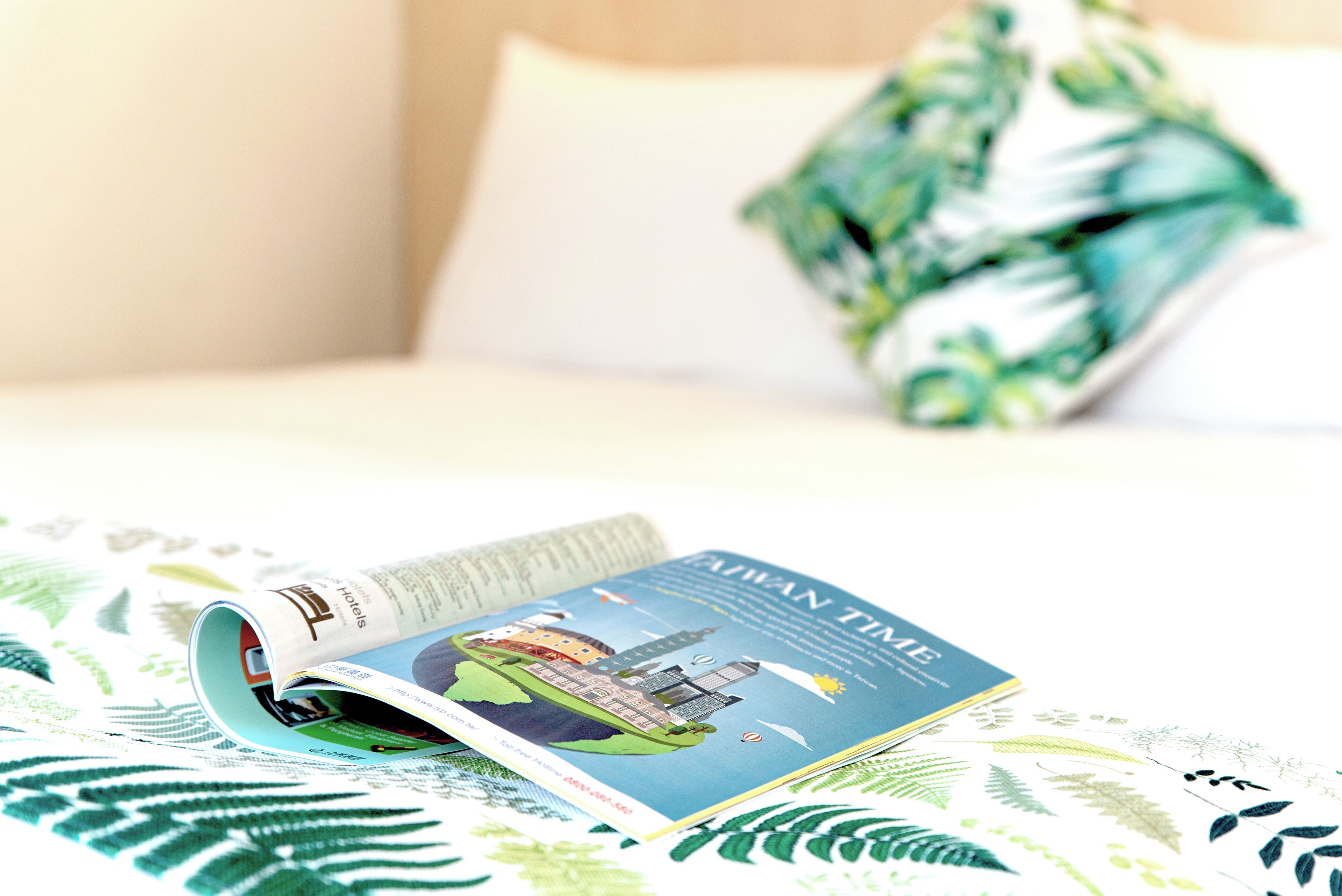 A magazine on a bed with a green leaf pattern.