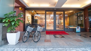 A hotel entrance with a red carpet, a bicycle, and a potted plant. - Liga Hotel (Hualien City)