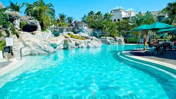 Relax by the resort pool surrounded by lush vegetation and natural rock formations.
