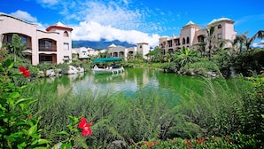 A resort with a central pond, surrounded by lush greenery and buildings with Mediterranean architecture. - Promisedland Resort & Lagoon (Shoufeng)