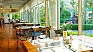 A restaurant with large windows, wooden tables, and chairs. - Promisedland Resort & Lagoon (Shoufeng)