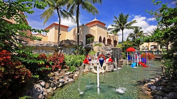 Relax by the clear pool surrounded by lush plants and a small waterfall.