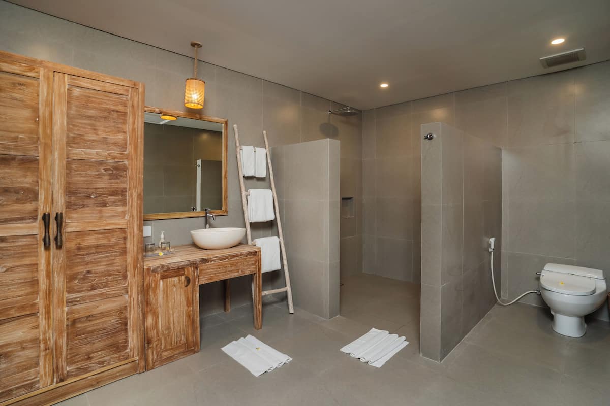 Un baño moderno con tocador de madera, un espejo grande, un lavabo blanco y zona de ducha.