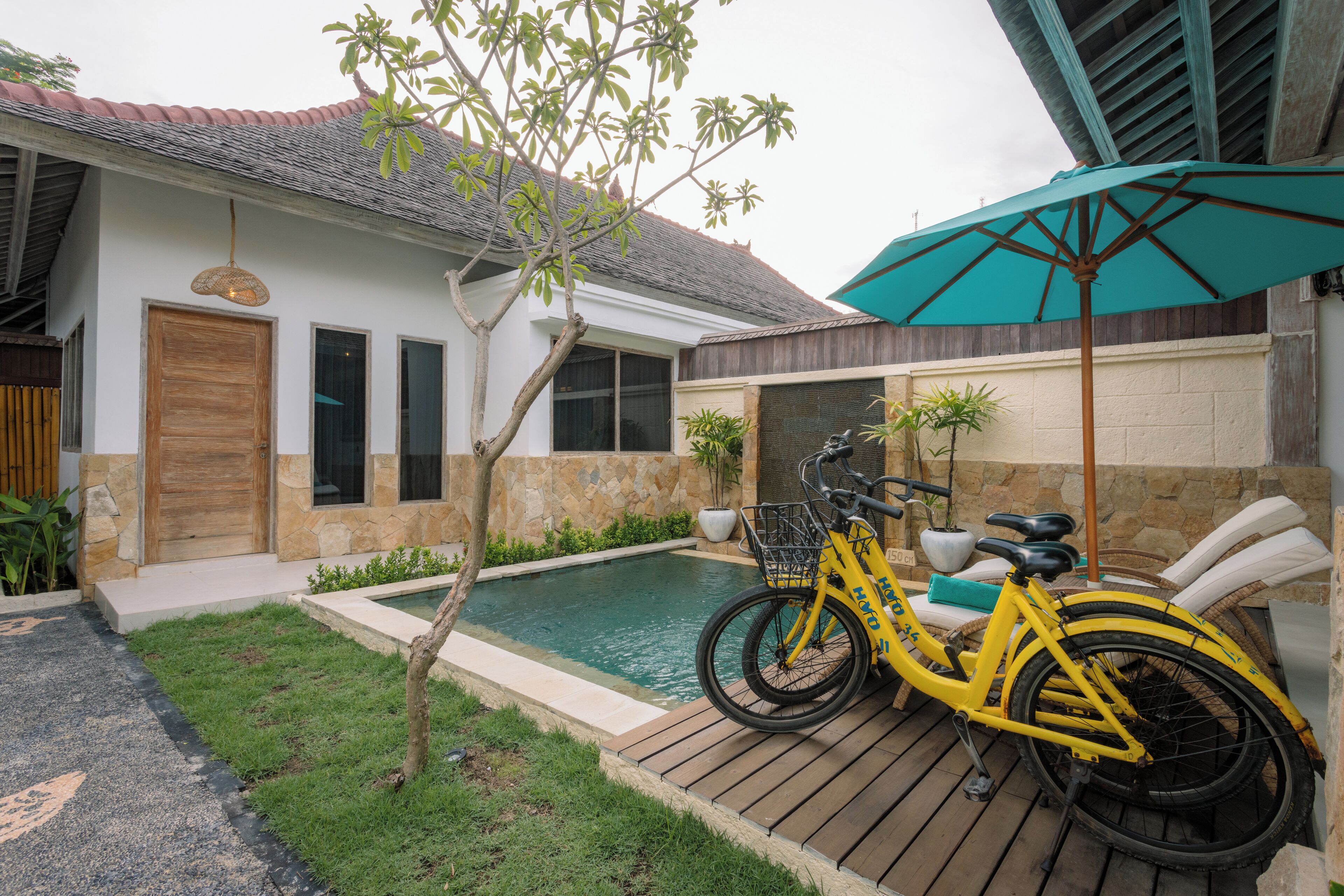 Una casa con piscina, terraza de madera y una bicicleta estacionada afuera.